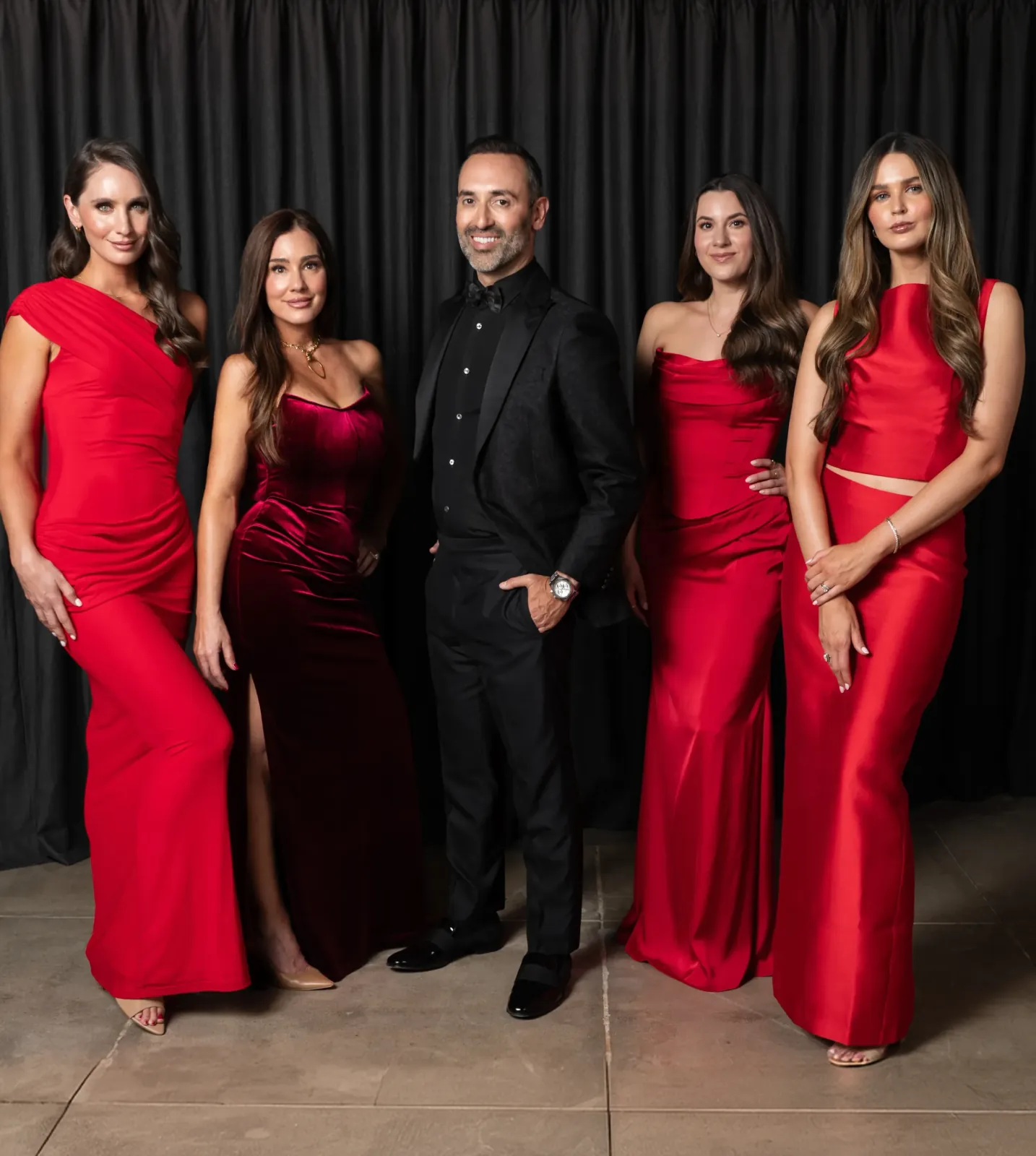 The Rewind Aesthetics providers in red gowns with Dr. Karimi in a black suit