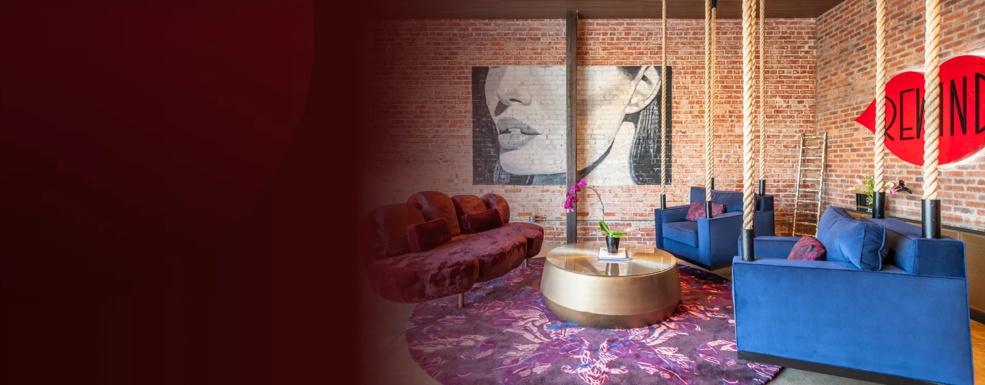 Rewind Aesthetics lounge with brick walls, rope columns, blue velvet chairs and the red Rewind lips sign