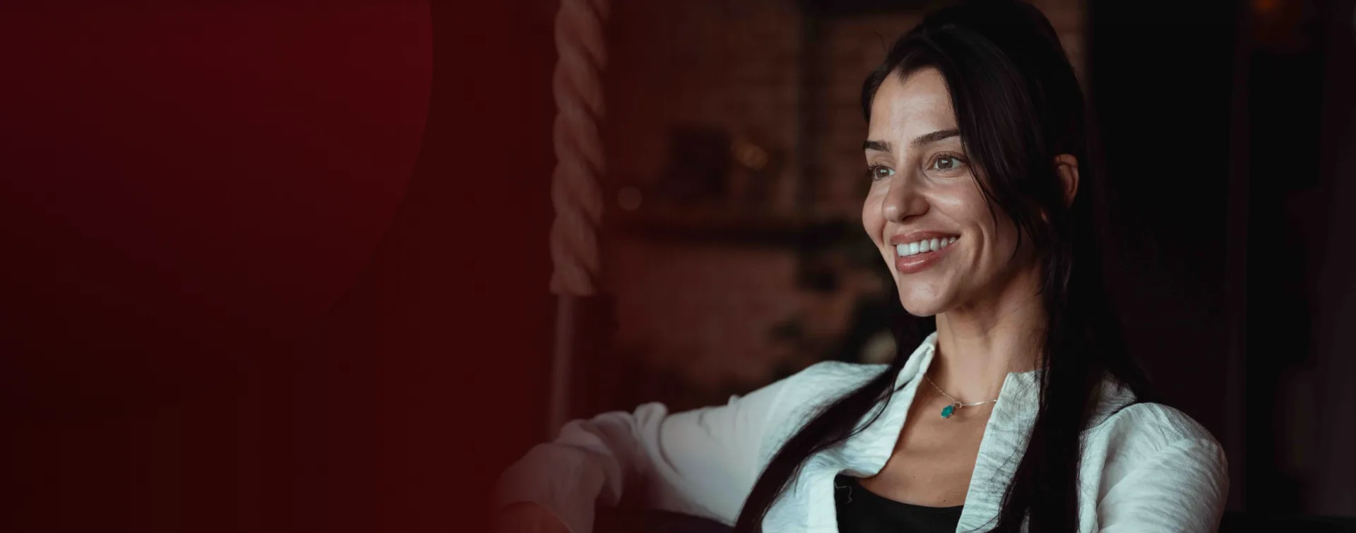 A smiling Rewind Aesthetics client relaxing in the brick-walled lounge