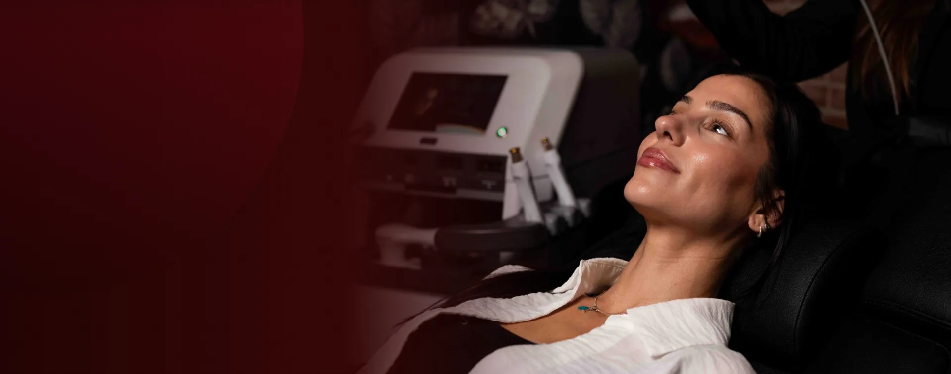 A client reclining in the treatment chair beside an energy-based device at Rewind Aesthetics
