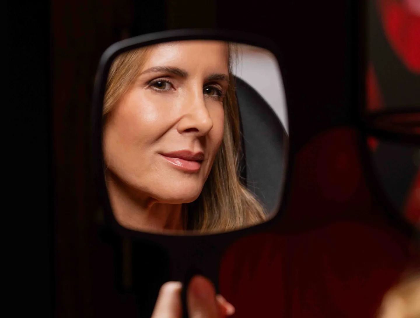 A woman checking her skin in a hand mirror