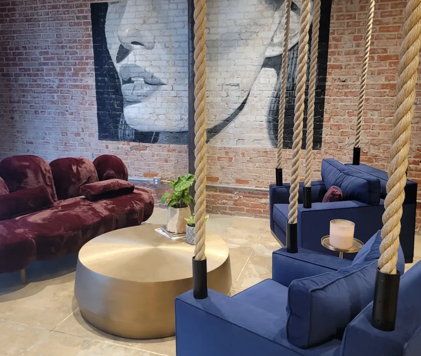 The Rewind lounge with velvet sofas, rope swing chairs and a face mural on the brick wall
