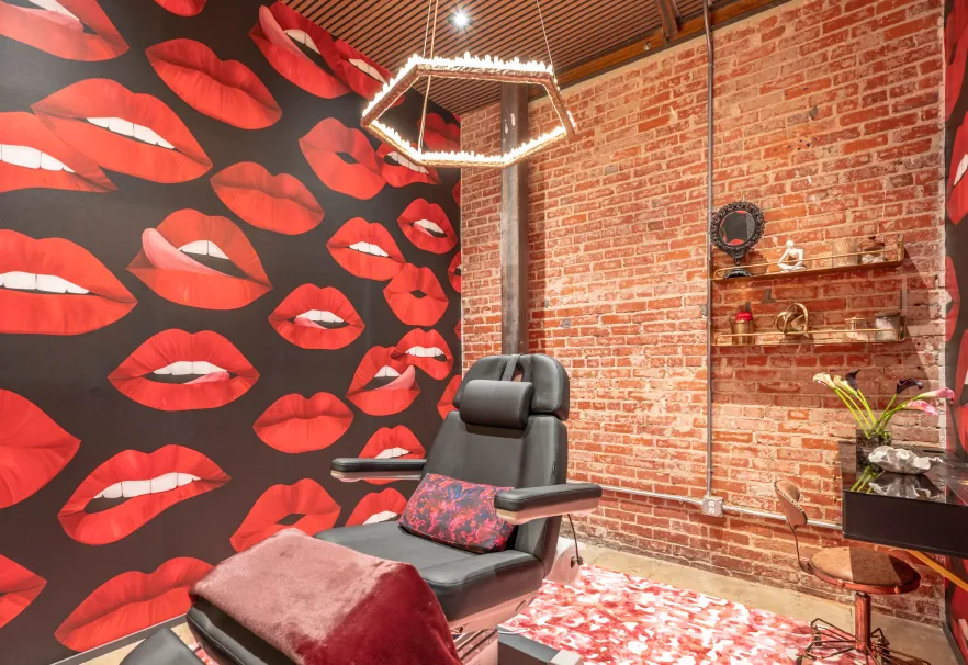 Treatment room with red lips wallpaper and brick walls