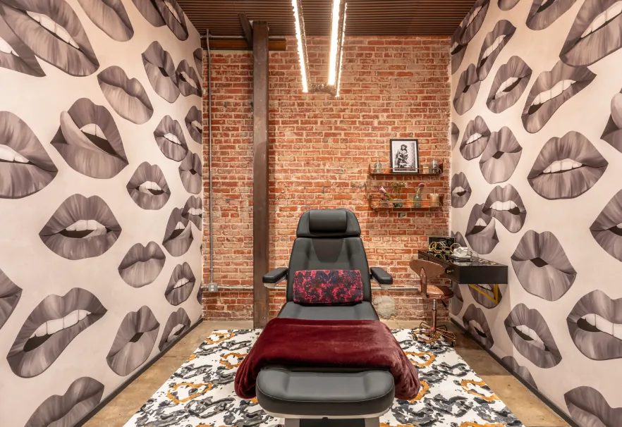 Treatment room with black-and-white lips wallpaper and a red chair