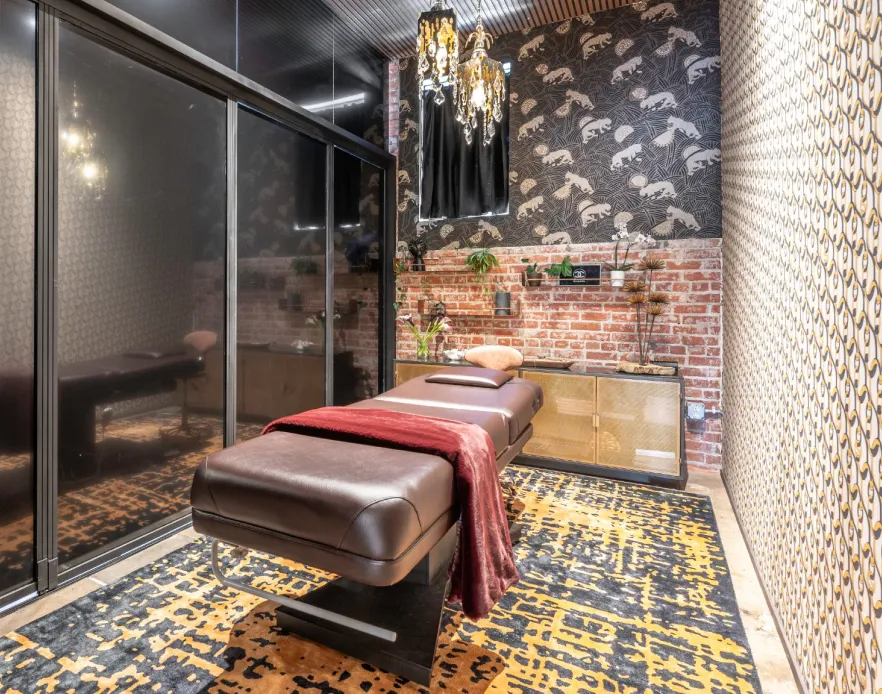 Treatment room with a leather bed, red throw and gold-patterned rug