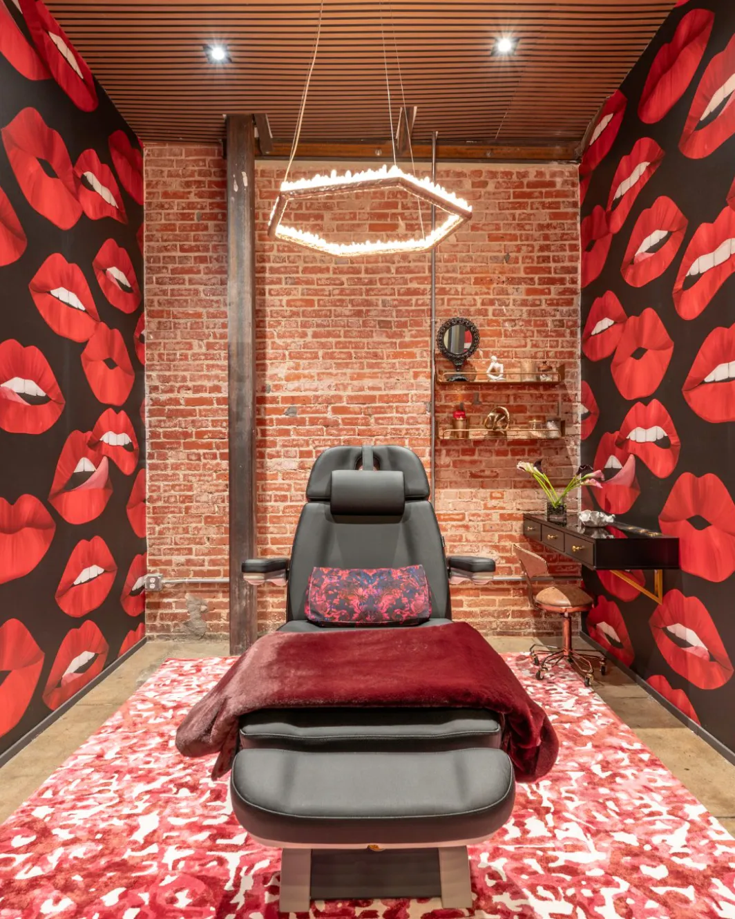 Treatment room with red lips wallpaper, brick walls and a rose-petal rug
