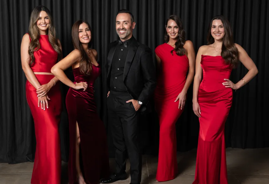 The Rewind Aesthetics team in red gowns with Dr. Karimi in a black suit